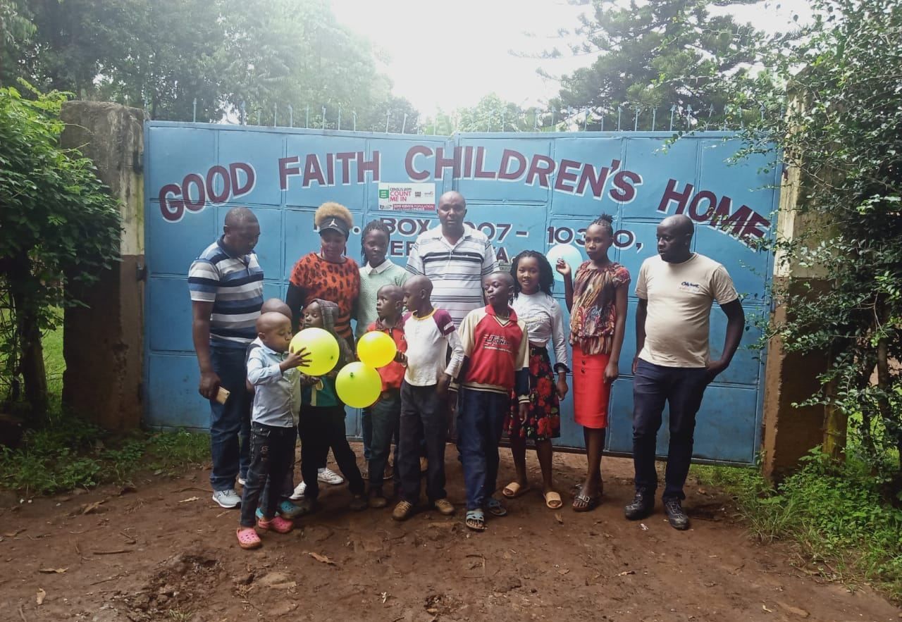 Children and staff with balloons in front of a children's home gate